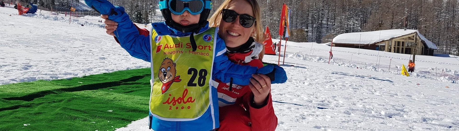 Un moniteur de ski de l'école de ski ESF Isola 2000 est aux côtés d'un enfant dans le jardin d'enfants, prêt à commencer le Cours particulier de ski Enfants pour Tous niveaux.