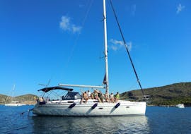 A sailing boat from DayCharter.es is on the crystal clear waters of the bay of Palma de Mallorca with the beautiful coastline.