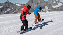 The snowboarding instructor of Schweizer Skischule Saas-Fee shows new tricks on the board to one of his customers during the private snowboarding lessons for kids and adults in the Valais.