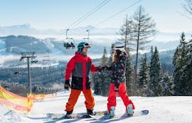 Ein Snowboardlehrer hilft einer Schülerin beim Privaten Snowboardkurs für alle Levels & Altersgruppen mit Skischule Olympic Hugo Nindl Axamer Lizum.
