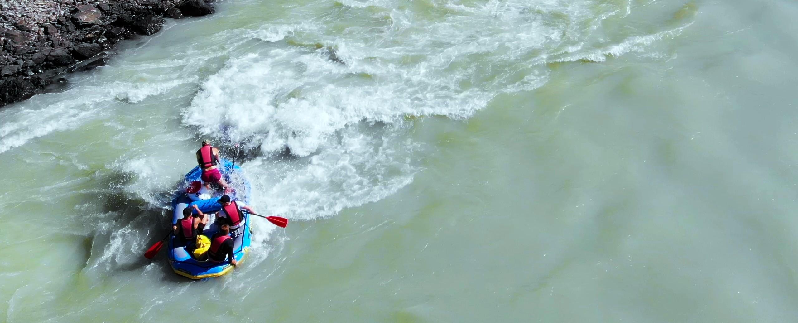 Gemeinsam mit ihrem Guide meistert eine Gruppe von Raftern eine kleine Stromschnelle auf dem Inn während ihrer Country-2-City-Rafting-Tour von Mötz nach Innsbruck mit Hi5 Austria.
