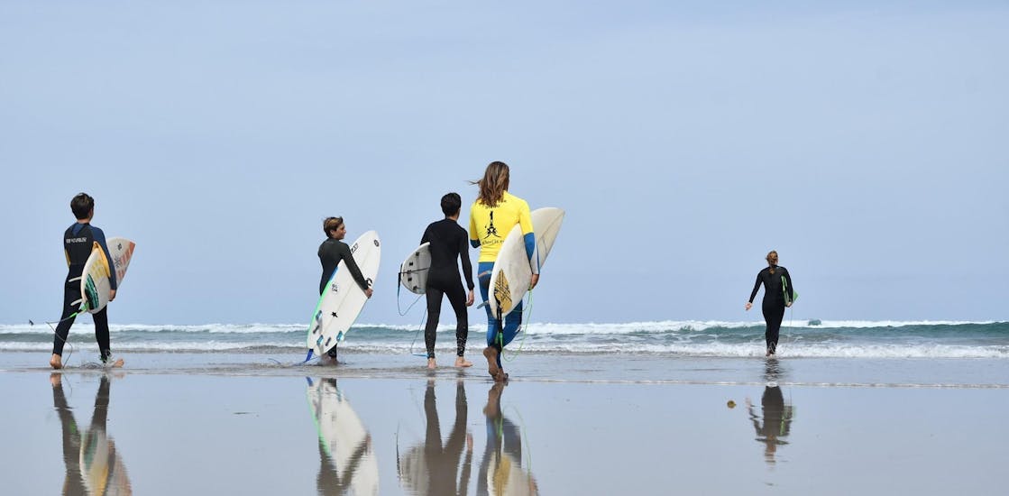 Eine Gruppe von Menschen am Strand während des Surfunterrichts am Famara Beach mit der Surf & SUP School3S Lanzarote.