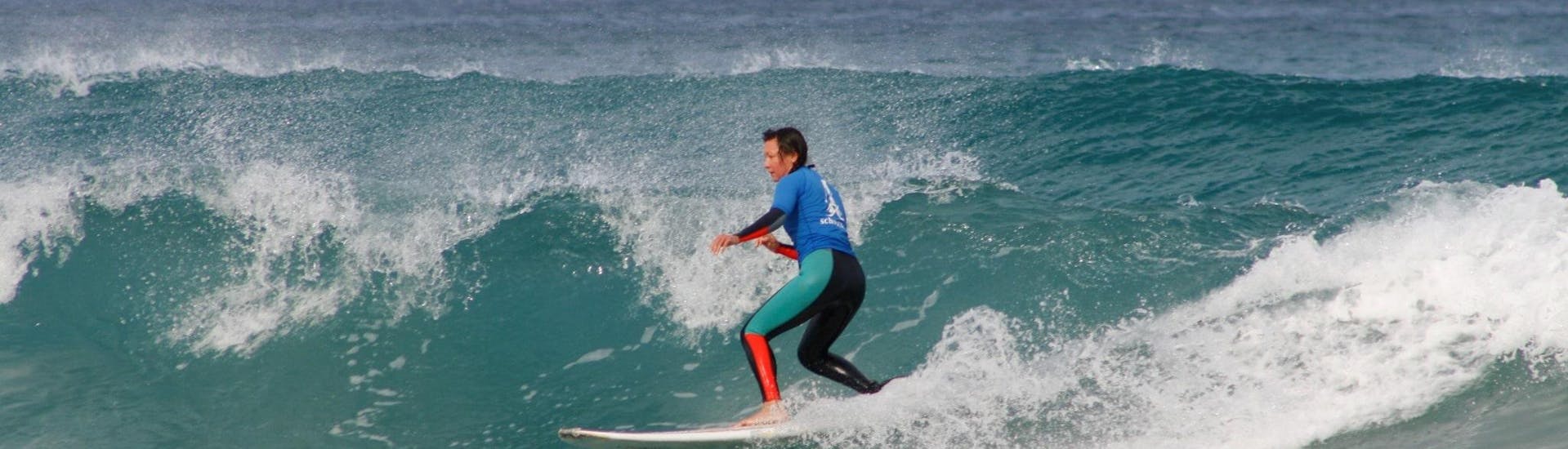 Une personne surfe sur une vague pendant les leçons privées de surf sur la plage de Famara avec l'école de surf et de SUP3S Lanzarote.