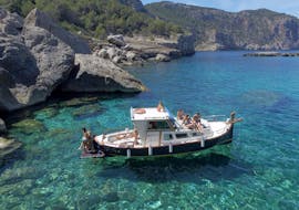 A boat from Take Off Ibiza is floating in the crystal clear waters during a private boat trip along the coast of Ibiza.