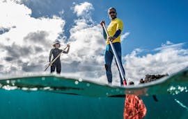 Twee deelnemers manoeuvreren met hun boards tijdens een les stand up paddleboarden in Puerto del Carmen met Surf&SUP School3s Lanzarote.