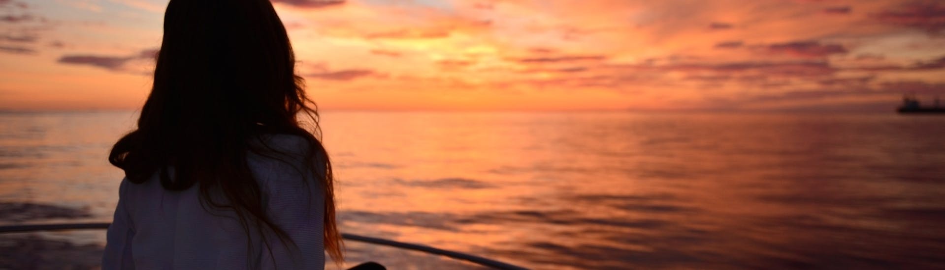 Una mujer admira la puesta de sol durante una excursión privada en barco por la costa de Ibiza con Take Off Ibiza.