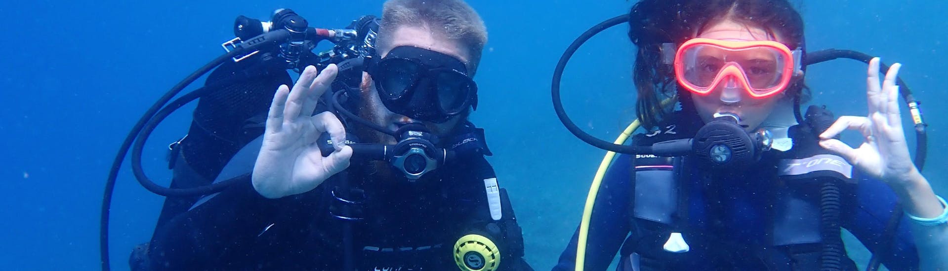 Two friends are underwater, doing one of their mandatory open water dive during their FFESSM Level 1 Diving Course in Fréjus for Beginners with Alpha Beluga Plongée.