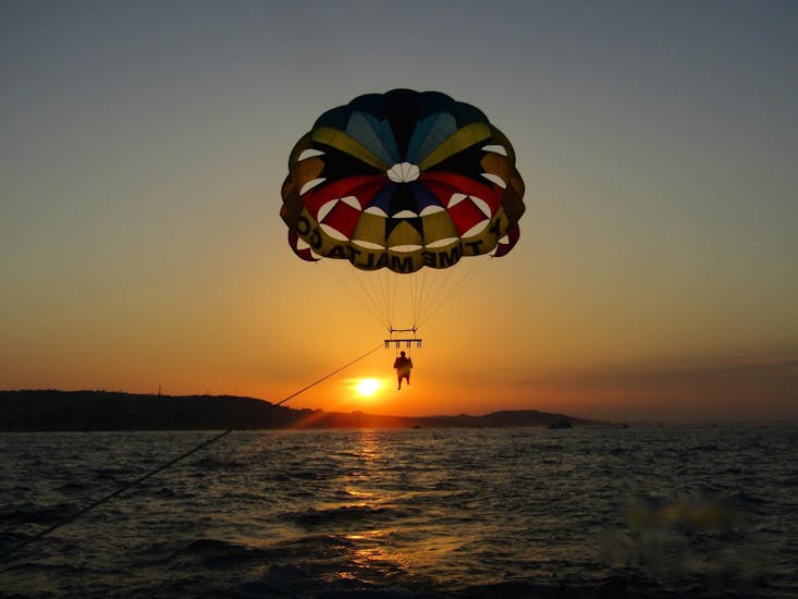 A guy enjoys the view of Malta's coastline from above at sunset during Parasailing in St.George's Bay with Flytimemalta.