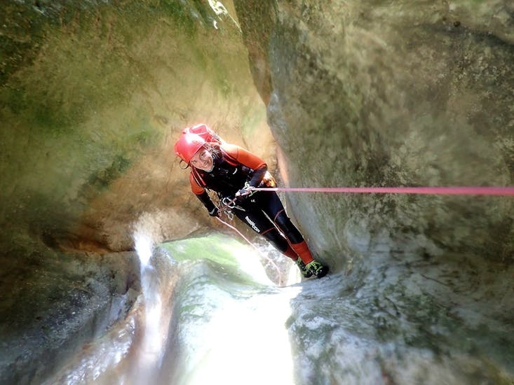 Donna sorride alla fotocamera mentre si cala con corda durante il canyoning Abseildown con SKYclimber Tremosine.