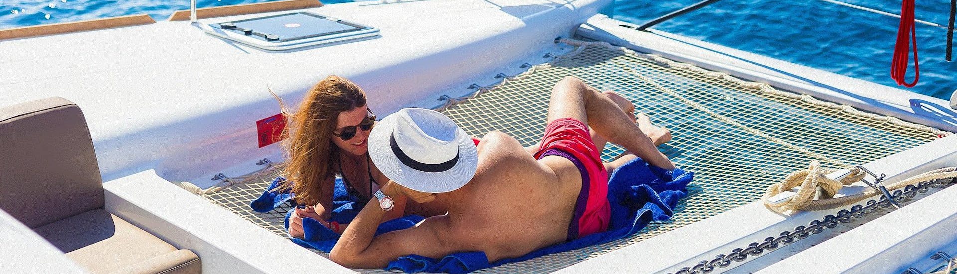 A couple is enjoying one of the sunbathing nets during their Luxury Catamaran Cruise around the Hotspots of Santorini with Spiridakos Sailing Cruises.