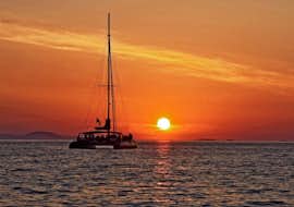 Luxury Sunset Catamaran Cruise around Santorini w/ BBQ & Cocktails from Spiridakos Sailing Cruises Santorini Catamaran on the water, with the sunset in the back.