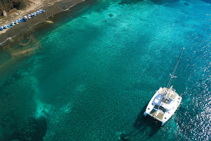 Bovenaanzicht van de boot tijdens de zonsondergang catamaran tour in Santorini met Spiridakos Sailing Cruises Santorini.