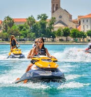 Two girls are riding their Jet Ski along the coast of Trogir after they rented it from Jet Ski Safari Trogir.