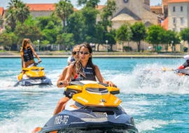 Zwei Freundinnen fahren mit ihrem Jet Ski entlang der Küste von Trogir, nachdem sie ihn bei Jet Ski Safari Trogir gemietet haben.