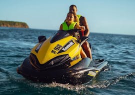 A child and his father are taking part in a jet ski initiation in the Cousteau reserve under the sunset with Iron Jet Bouillante.