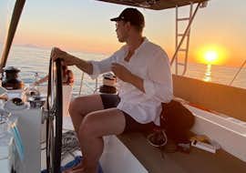 Private Katamarantour um Santorini bei Sonnenuntergang mit Spiridakos Sailing Cruises Santorini Ein Gast von Spiridakos Sailing Cruises genießt seine Zeit auf einem Katamaran während einer Bootstour bei Sonnenuntergang entlang der Hotspots von Santorini.
