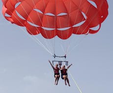 Dos amigos disfrutan de la maravillosa vista de la costa maltesa desde arriba, mientras vuelan en el cielo durante un viaje en parasailing en Mellieha Bay, con Oh Yeah Malta.
