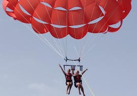 Drie vrienden genieten van het prachtige uitzicht op de Maltese kust van bovenaf, terwijl ze vliegen in de lucht tijdens het parasailen bij Mellieha Bay met Oh Yeah Malta.