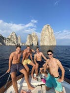 Cuatro chicos posando frente a las rocas Faraglioni durante el clásico viaje en barco de Sorrento a Capri, con Lubrense Boats Amalfi Coast.