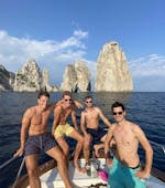 Vier junge Männer posieren vor den Faraglioni während der klassischen Bootsfahrt von Sorrent nach Capri mit Lubrense Boats Amalfiküste.