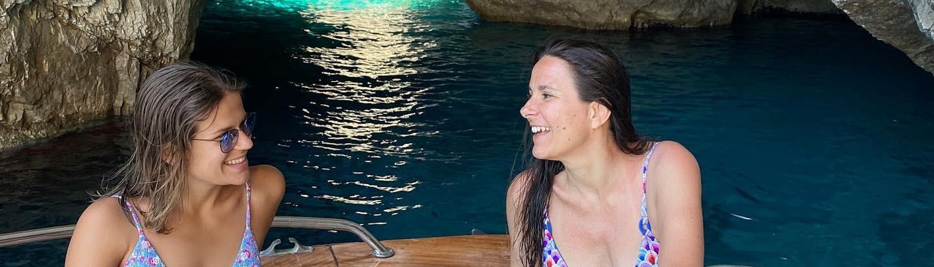 Due amiche parlando e ridono durante il giro in barca privato da Sorrento a Capri con Lubrense Boats Costiera Amalfitana.