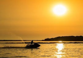 Die Silhouette eines Jetskis von Jet Ski Rent Dubrovnik und seines Fahrers, der in den Sonnenuntergang fährt 