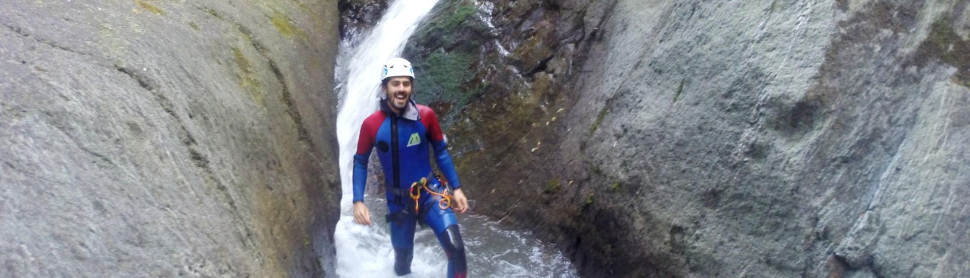 A young man can be seen wading through the water in a narrow ravine while Canyoning in Rio Vallungo - Water Park with Canyoning Valle D'Aosta.