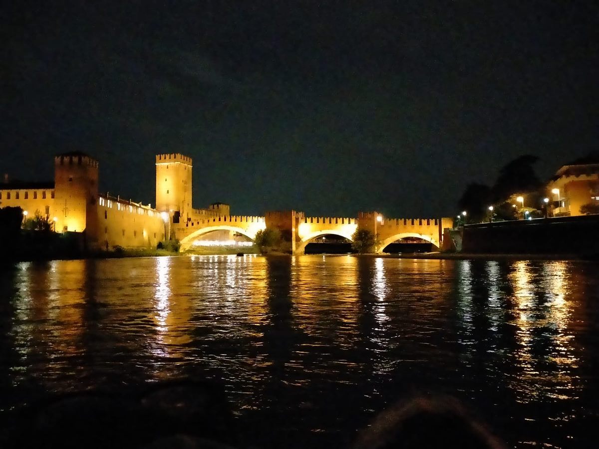 Un gruppo di partecipanti al tour di rafting sta passando sotto un ponte durante il Moonlight Rafting sul fiume Adige attraverso Verona con Pescantina Rafting Bussolengo.