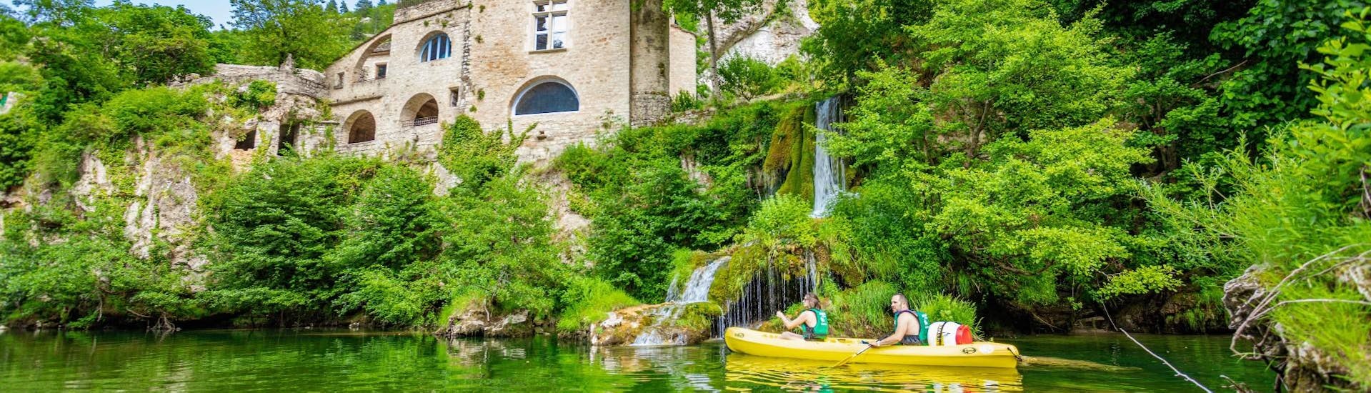 A family is paddling under the cascade of Saint-Chély during the 7 km Canoe Hire for families with canoe Méjean Sainte-Énimie.
