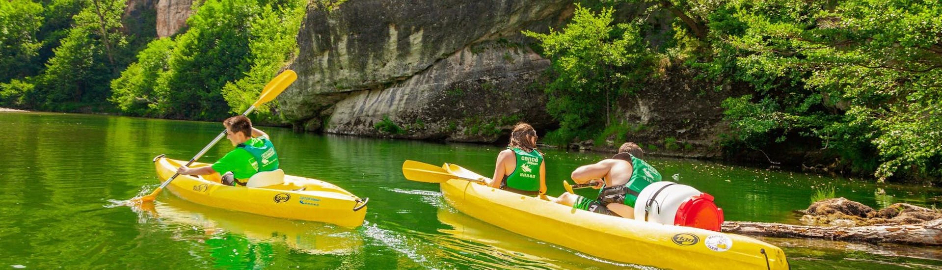 Une famille sur ses canoës contemple la nature de la rivière Tarn lors du circuit détente de 11 km avec le canoë Méjean Sainte-Énimie.
