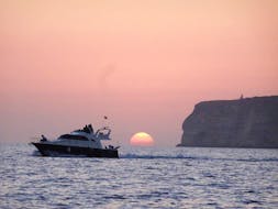Das Boot Liliana segelt während der von Gita in Barca Liliana Lampedusa organisierten Bootstour um Lampedusa bei Sonnenuntergang mit Abendessen über das Meer.
