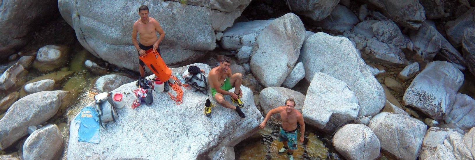Trois hommes font une pause dans le Canyon pendant sa journée sportive de canyoning dans le Canyon de Fiumorbu avec Acqua et Natura.