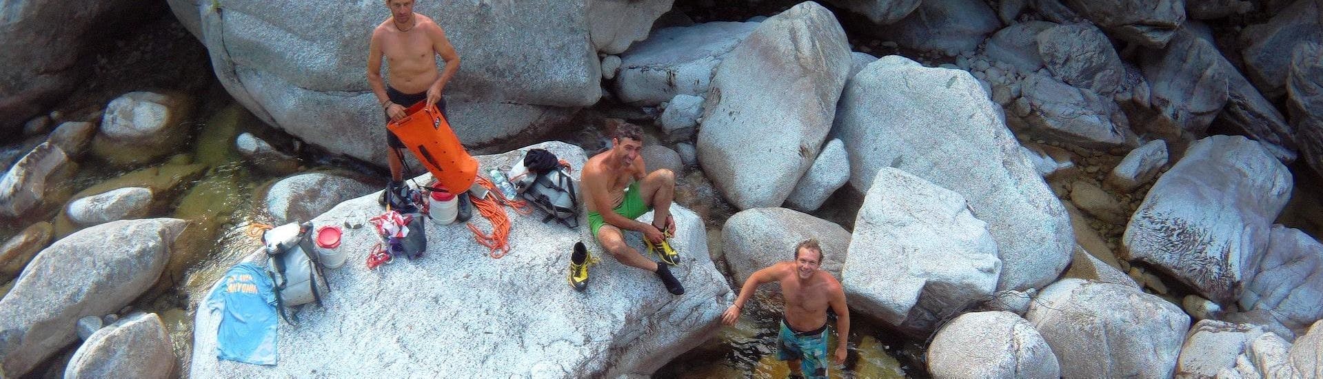 Drei Männer legen beim sportlichen Ganztages-Canyoning im Canyon de Fiumorbu mit Acqua et Natura eine Pause in der Schlucht ein.
