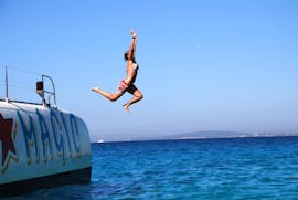 A woman is jumping from the boat of Magic Catamarans into the water while on their catamaran tour around the bay of Palma de Mallorca.