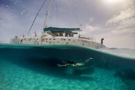 Una mujer se sumerge en el agua junto a un barco de Magic Catamarans en su paseo en catamarán a illetes desde Palma de Mallorca.