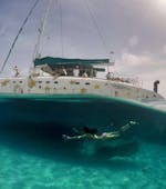 A woman is diving in the water next to a boat from Magic Catamarans on their catamaran tour to illetes from Palma de Mallorca.