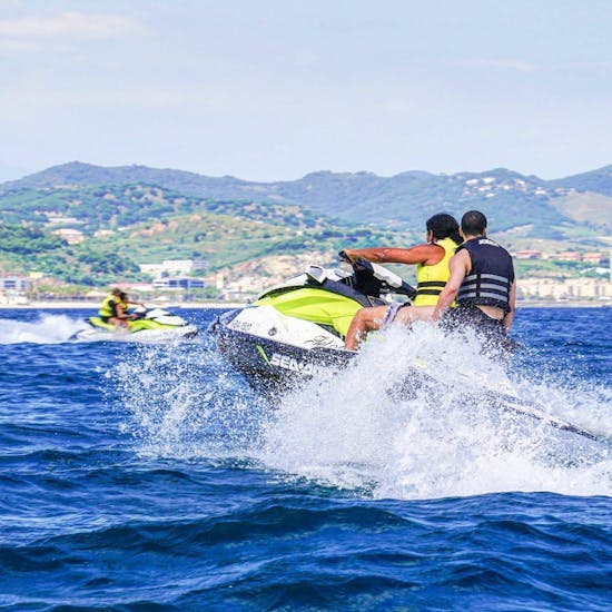 Two men on a Sea Riders jet ski ride along the coast of Barcelona.