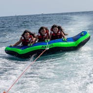 Drie vrouwen zitten bovenop de Crazy Boat van Sea Riders Badalona terwijl ze door een boot worden gesleept in de baai van Barcelona.