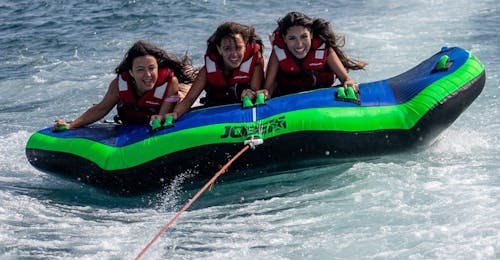 Crazy Sofa in Barcelona Bay from Sea Riders Badalona Three women are on top of the Crazy Boat of Sea Riders Badalona while being towed by a boat in Barcelona Bay.