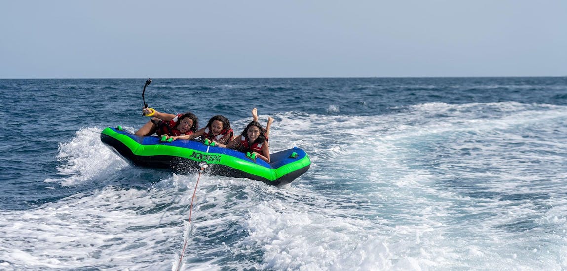 Drei Frauen an Bord einer Sea Riders-Schlauchmatratze, die von einem Boot vor der Küste Barcelonas abgeschleppt wurde.