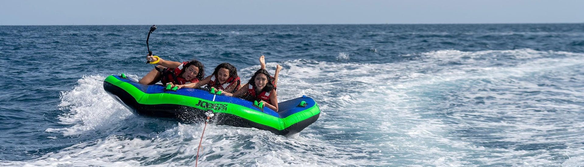 Trois femmes à bord d'un matelas gonflable Sea Riders remorqué par un bateau lors de leur activité Crazy Sofa à Barcelone.