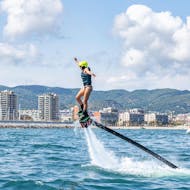 A woman is flyboarding with Sea Riders at a high altitude off the coast of Barcelona.
