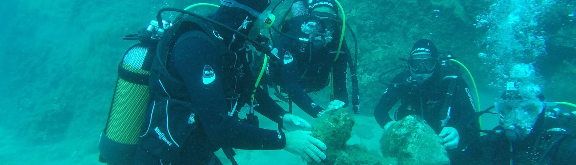 A diver and his instructor are exploring a statue underwater during the Trial Scuba Diving in Saint-Raphaël Bay with Dive Is Fun Fréjus.