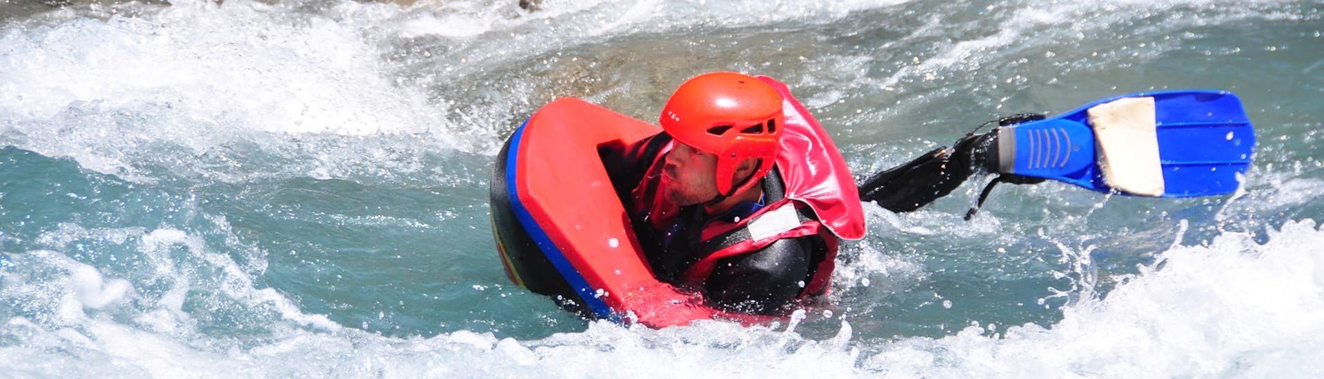 A man is surfing waves during his activity of Hydrospeed on the Ubaye River with Anaconda Rafting.