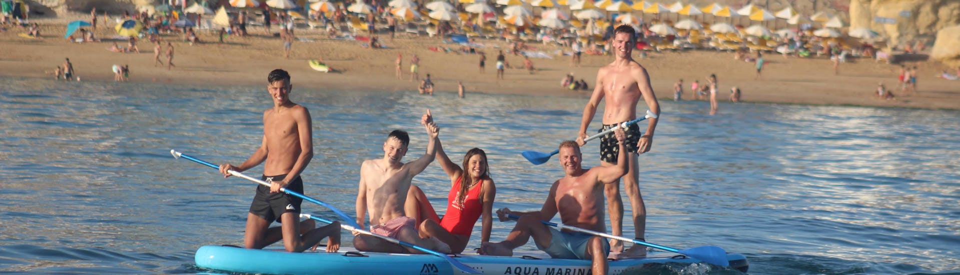 Une photo d'une famille profitant d'un Mega Stand Up Paddleboard à Armação de Pera loué chez Moments Watersports Algarve.