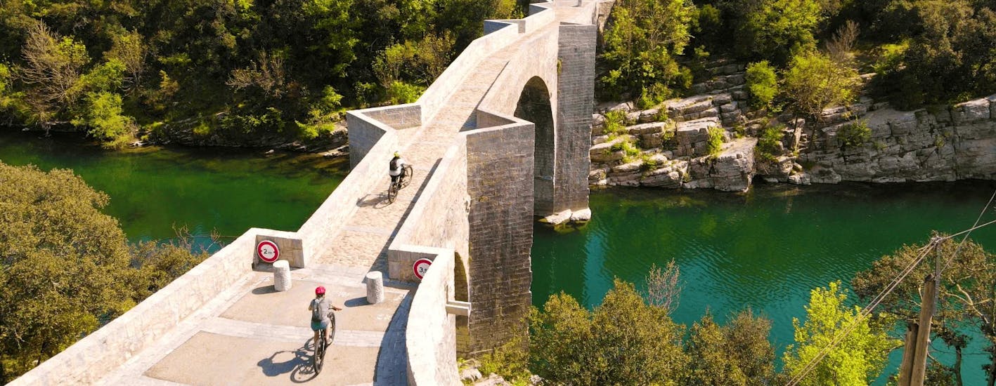 Des touristes passent sur le Pont du diable pendant la Location de vélo électrique à Saint-Jean-de-Buèges avec Le Garrel Hérault.
