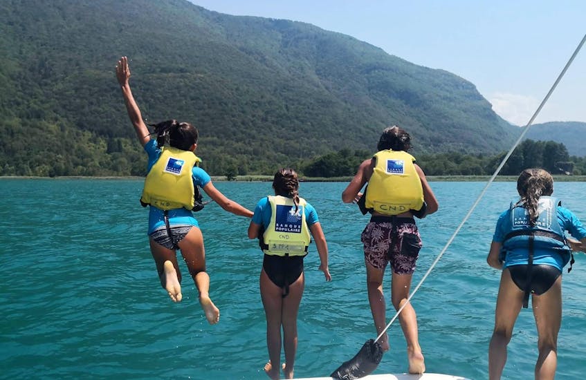4 Enfants sautant d'un catamaran lors de la Location de catamaran sur le lac d'Annecy avec Wake & Ski 74. 