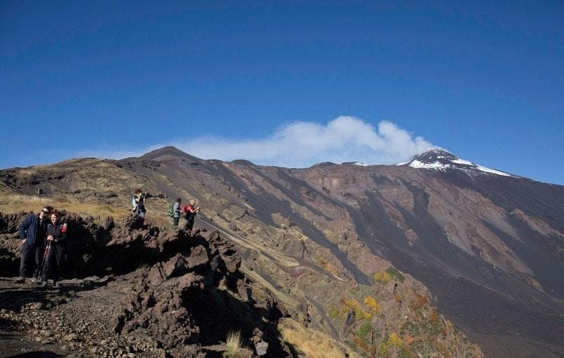 A group of people at the top of Mount Etna's crater during a trekking on Mount Etna with typical products tasting with Sicilia Adventure.
