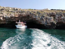 Une delle barche di Noleggio Nettuno Torre Vado visitando una grotta durante il giro in barca alle grotte del Salento con aperitivo.