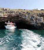 Une delle barche di Noleggio Nettuno Torre Vado visitando una grotta durante il giro in barca alle grotte del Salento con aperitivo.